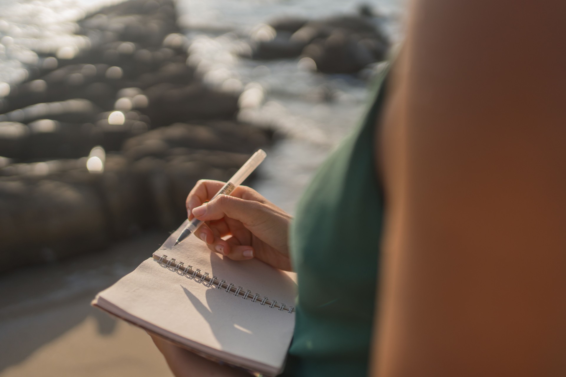 Young woman writes on notepad at beach
